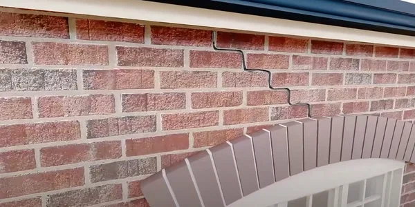 Arch & lintel repair — a Buildfix technician marking the cracks above the windows of a brick home before HelicalBar™ reinforcement