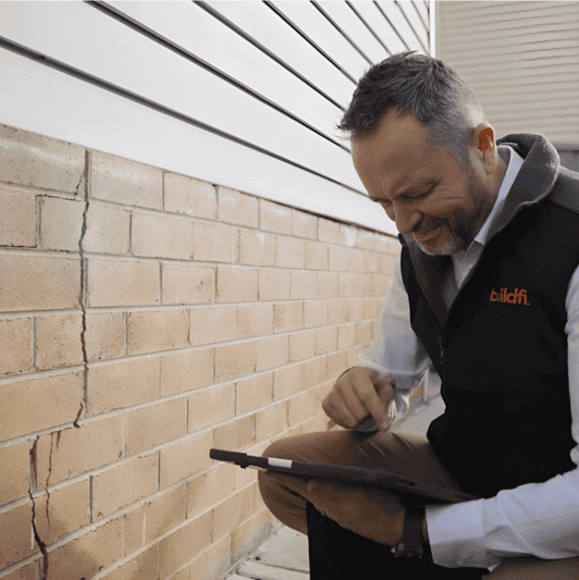 Structural repair expert assessing vertical wall crack for foundation subsidence risks.