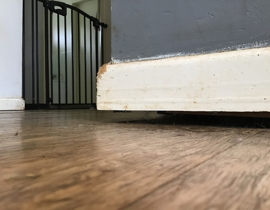 Damaged baseboard and chipped paint from subsidence, possible foundation repair needed.