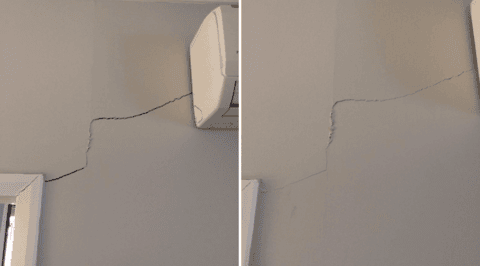 Diagonal wall crack beneath air conditioning unit indicating foundation subsidence issues.