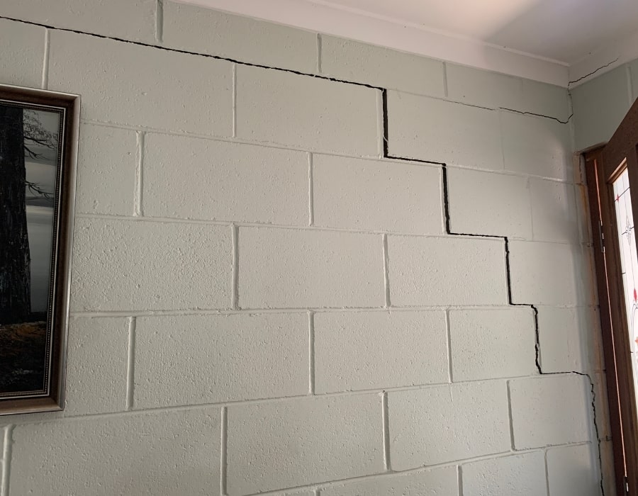 Zigzag wall cracks on painted cinder block indicate potential foundation subsidence issues.