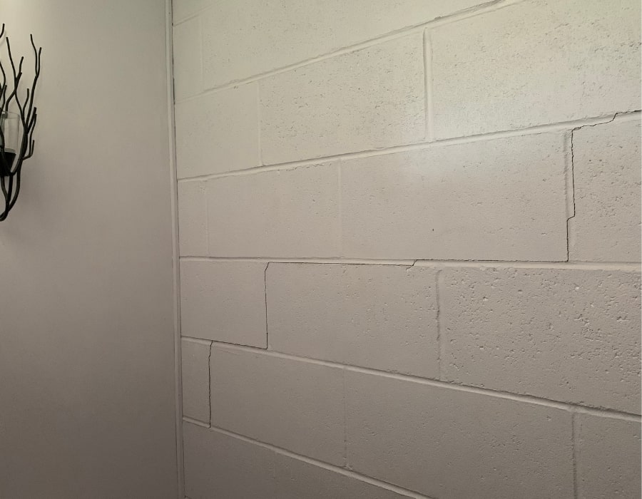 Wall cracks indicating potential subsidence and foundation repair needs in concrete block wall.