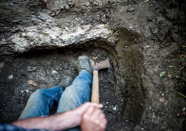 A builder digging footings for the concrete underpinning