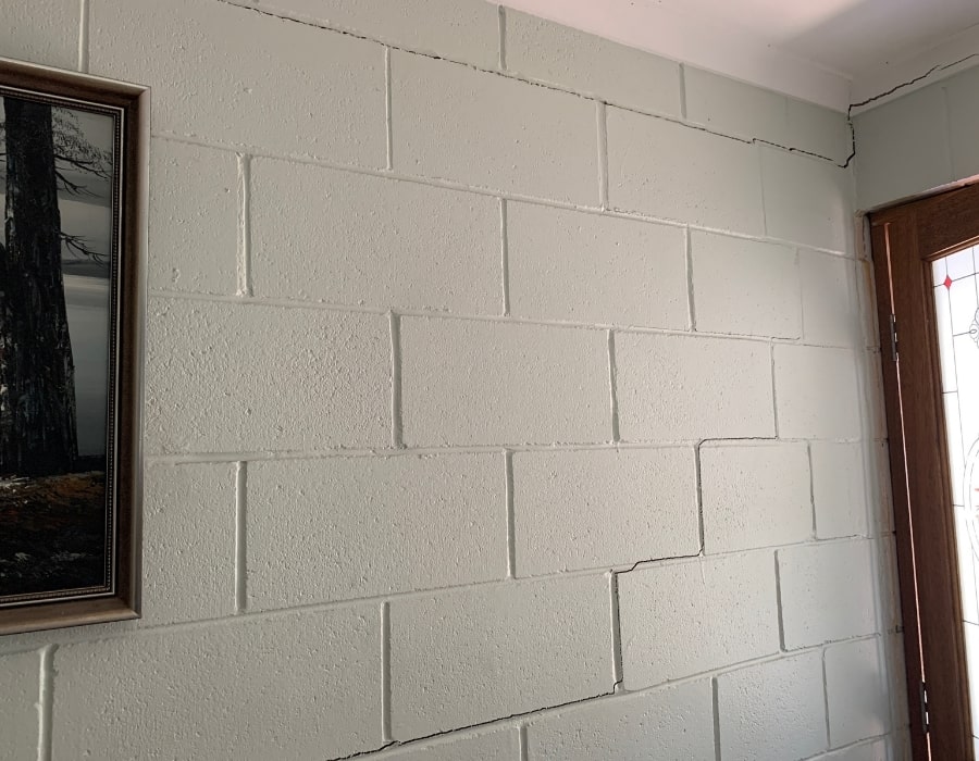 Painted cinder block wall displaying mortar line cracks and signs of subsidence.
