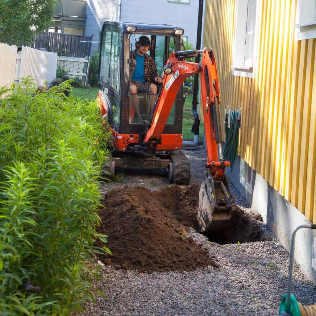 Builder using a digger in order to start concrete underpinning