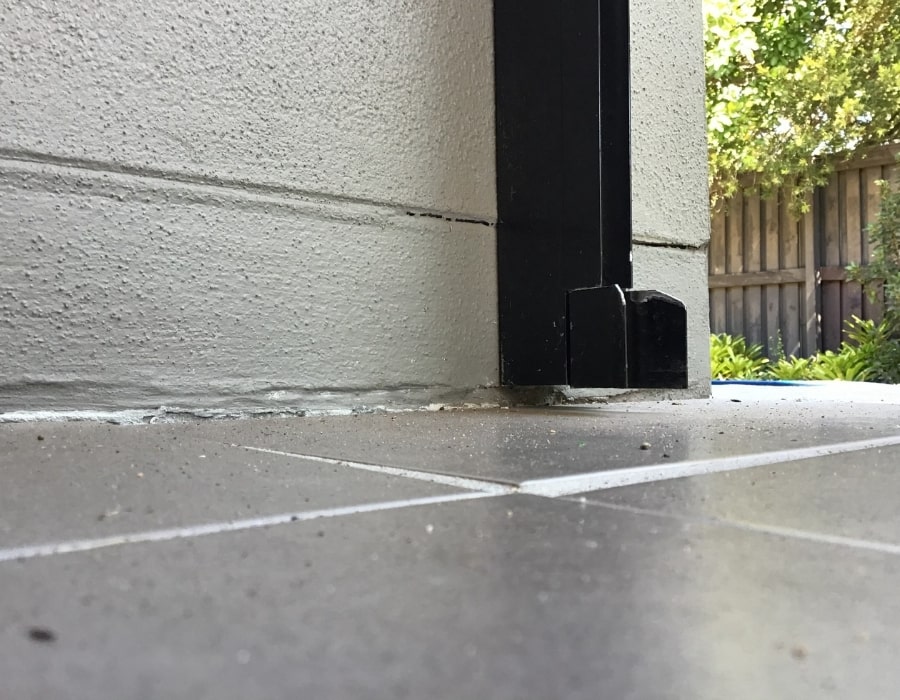 Tiled patio meeting cracked rendered wall indicating possible foundation subsidence repair needs.