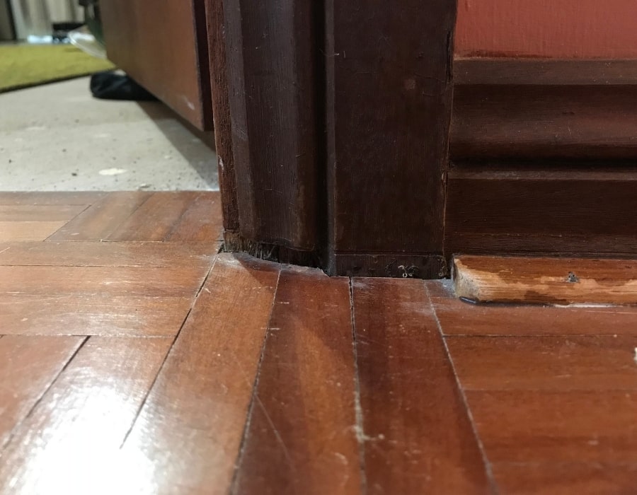 Visible floorboard gap near door frame indicating foundation subsidence or structural misalignment.