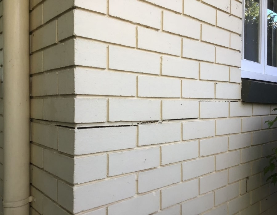 Horizontal wall crack near window indicates subsidence and foundation repair need.