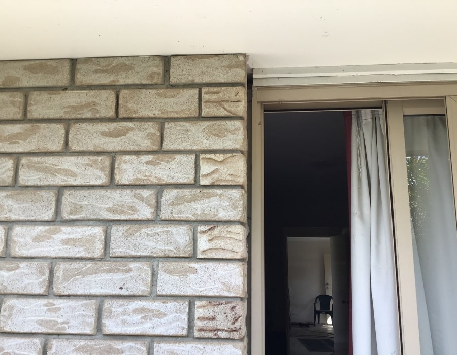 Sliding glass door by beige brick wall post-foundation repair to address subsidence.