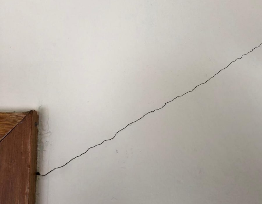 Diagonal subsidence crack above door frame indicating foundation movement wall cracks.