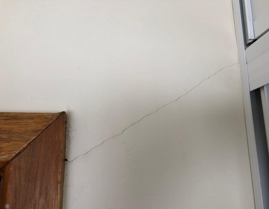 Diagonal wall crack near door frame signalling foundation subsidence and repair needs.