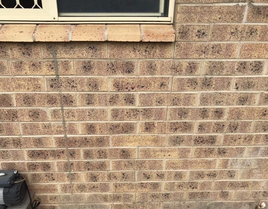Brick wall subsidence near window, early signs of foundation repair needed.