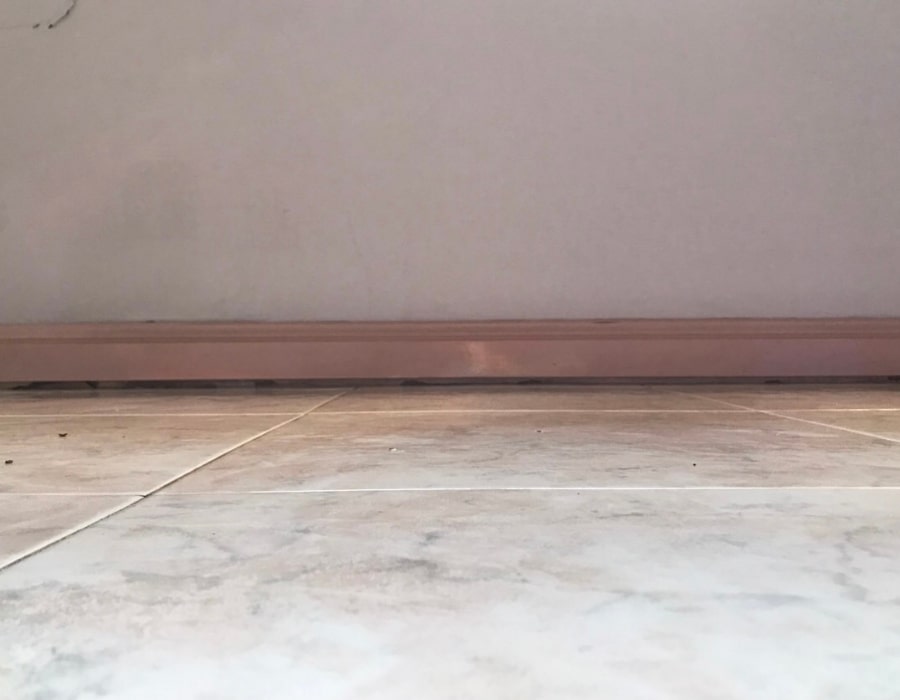 Dirt collecting at floor edge indicating potential rising damp or subsidence.