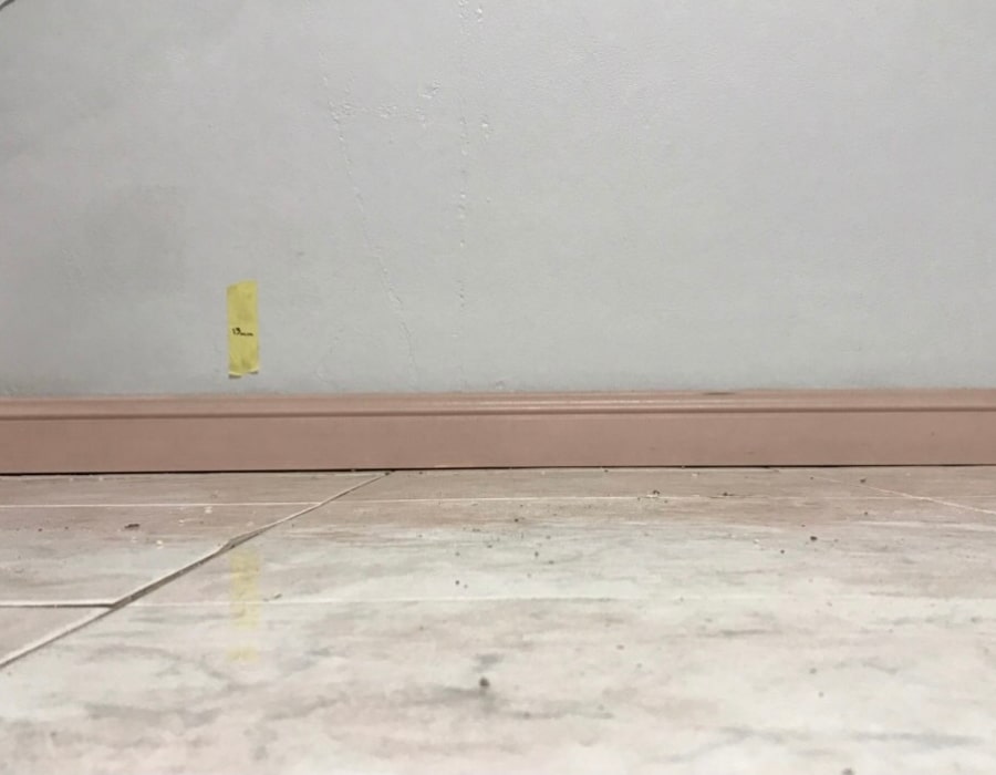 Tiled floor and baseboard showing early signs of rising damp issue.