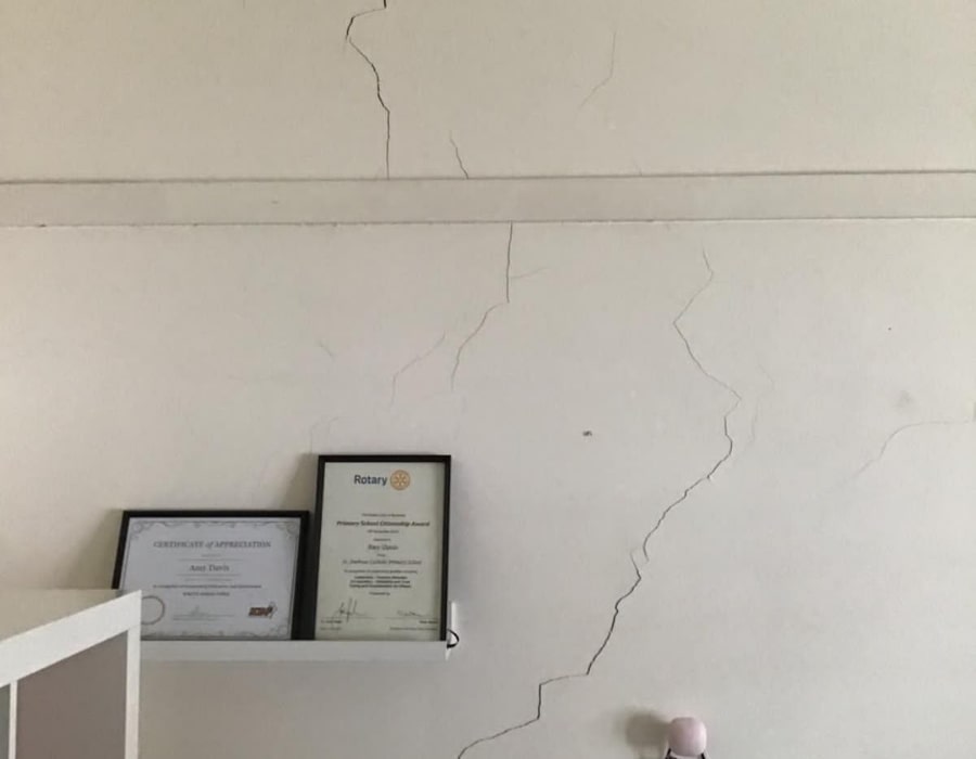 Long wall cracks above shelf indicating potential foundation subsidence and structural damage.