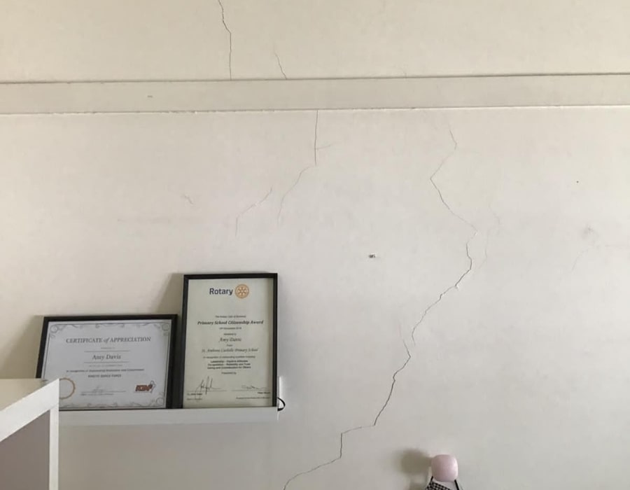 White internal wall with visible cracks indicating subsidence and foundation repair needs.