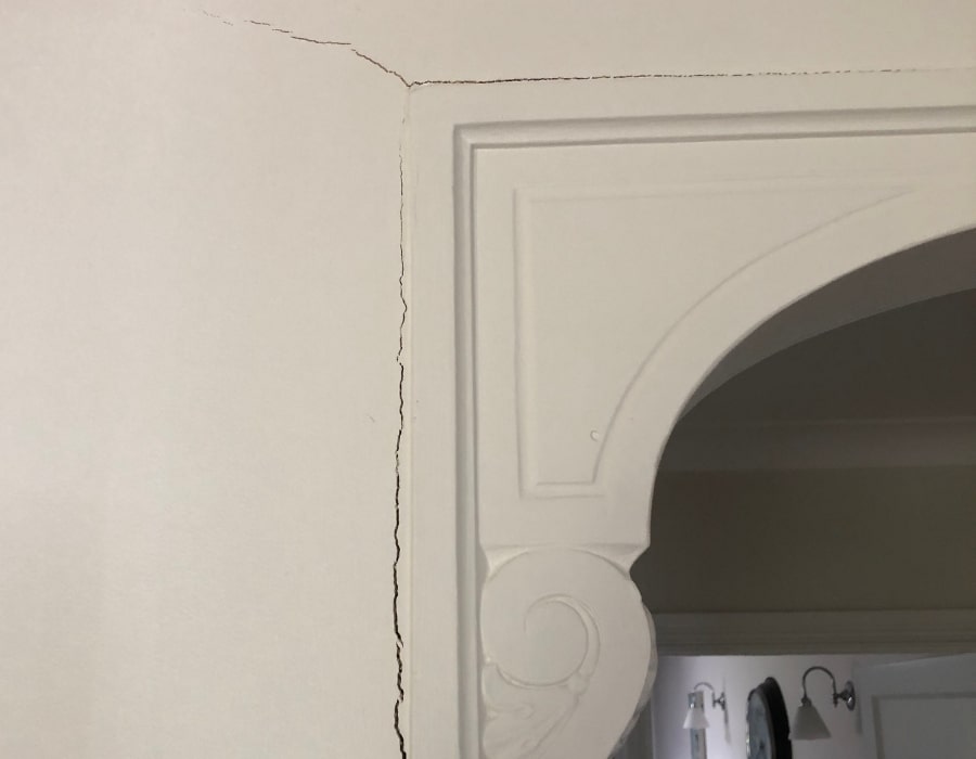 Vertical wall crack near ornate archway indicating subsidence and foundation repair need.