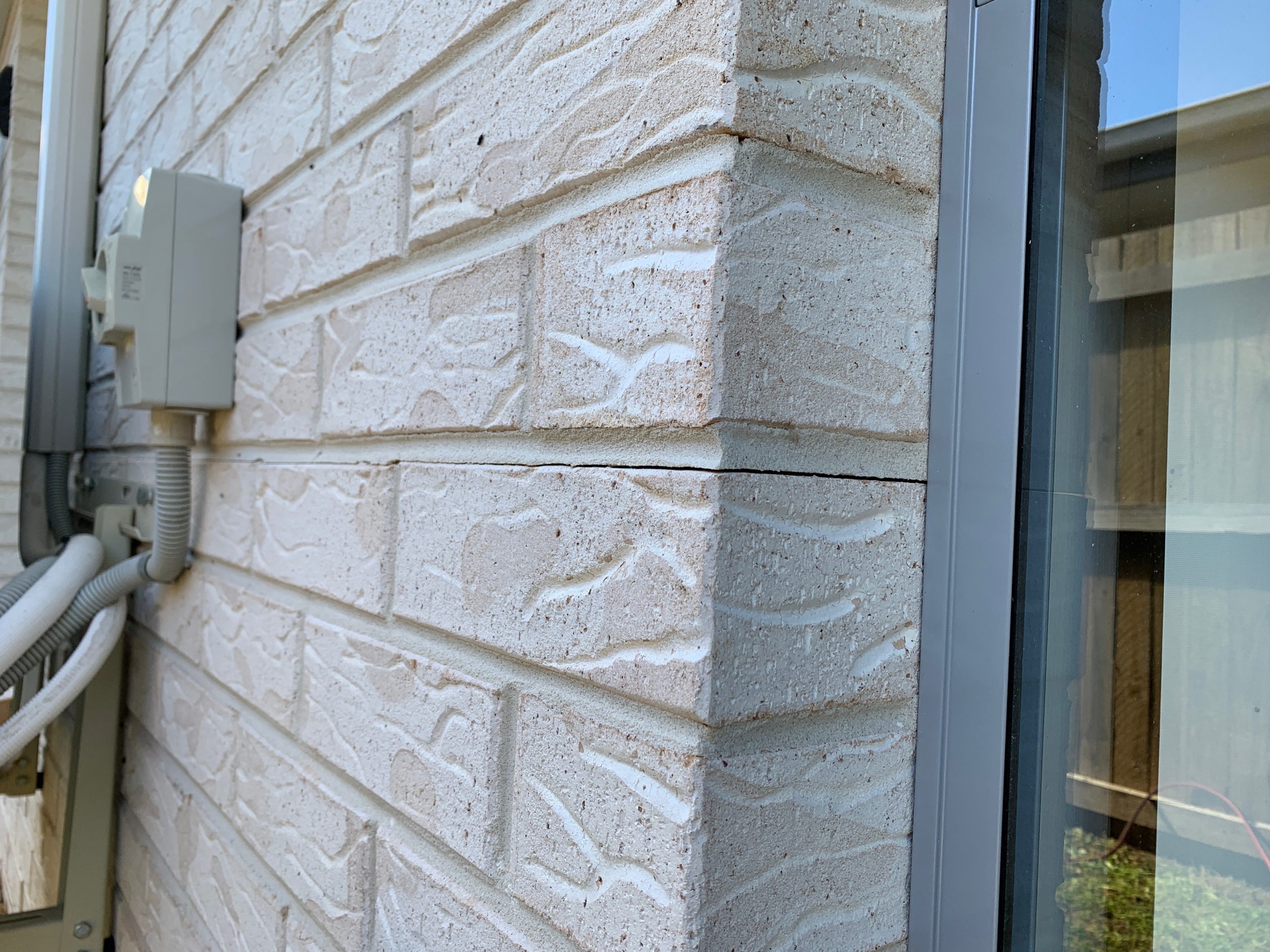 Foundation wall cracks near expansion joints indicating possible subsidence and rising damp.