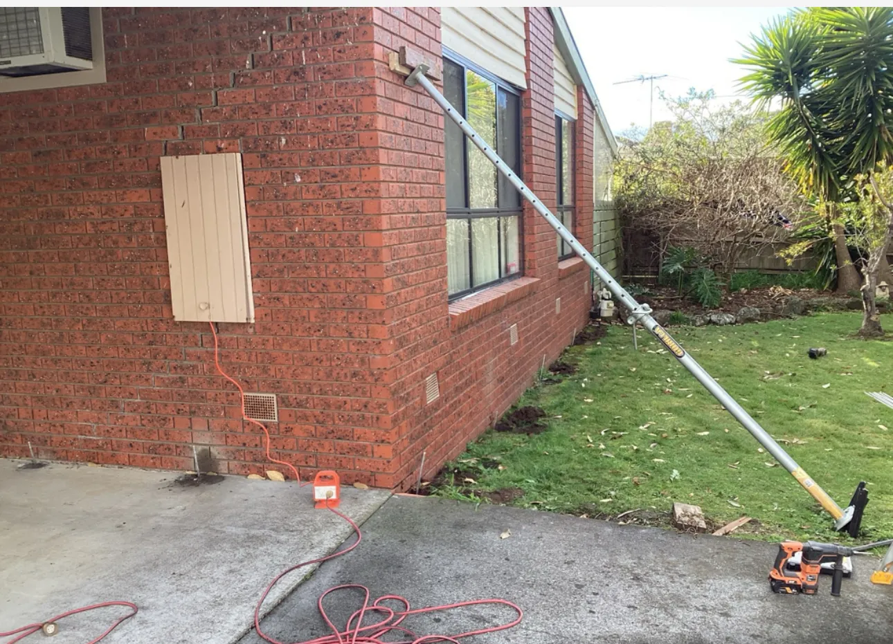Foundation repair underway with metal bracing pole stabilising brick wall subsidence.