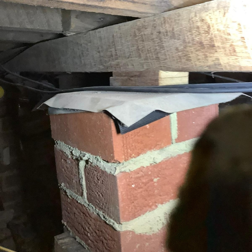 Brick pier foundation with moisture barrier preventing rising damp and wall cracks.