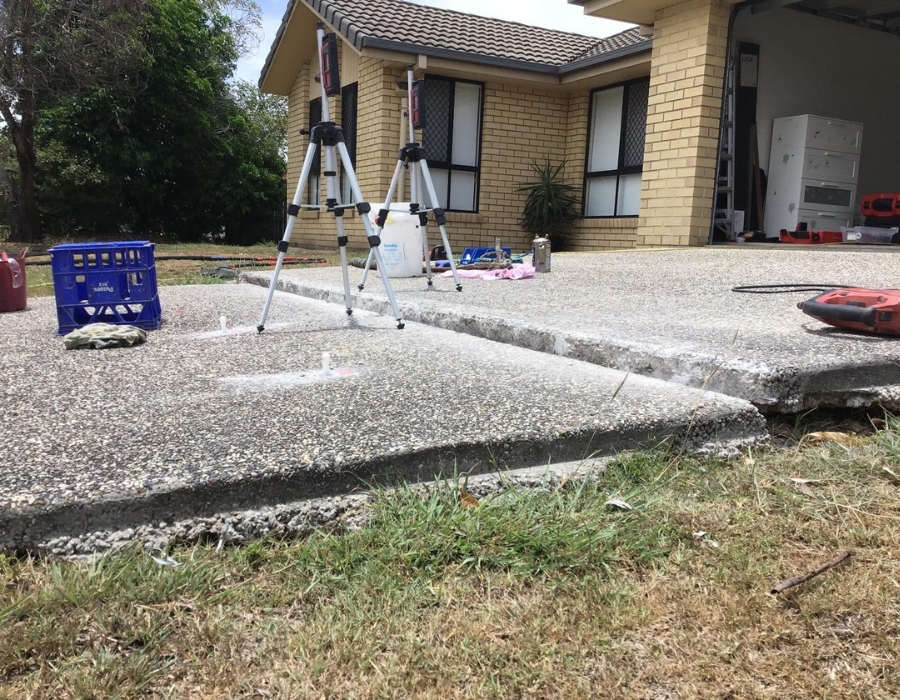 Cracked concrete driveway subsidence repair with GeoPoly equipment and tools onsite.