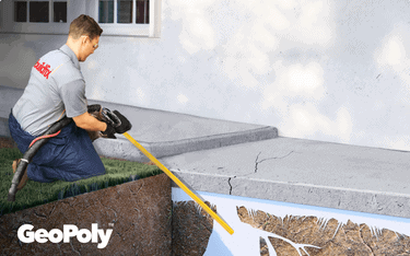 Worker injects GeoPoly under cracked concrete slab for foundation subsidence repair.