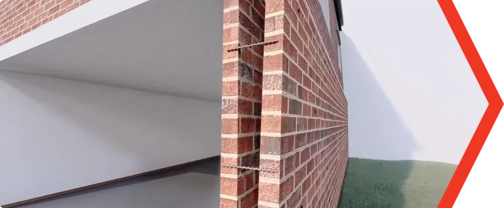 Brick wall corner with visible rising damp and interior foundation cracks.