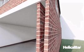 Brick wall separating from structure with HelicalBar reinforcement for foundation repair.