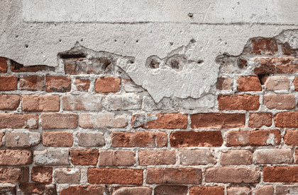 Chipped plaster exposes cracked brickwork indicating foundation subsidence and rising damp issues.