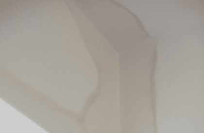 Ceiling corner with water stains indicating rising damp and possible subsidence.