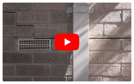 Brick wall with horizontal and vertical cracks indicating subsidence and foundation repair needs.