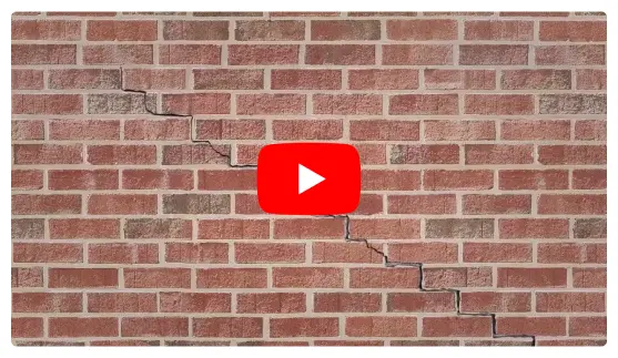 Jagged horizontal wall crack in red brick indicating structural subsidence repair needed.